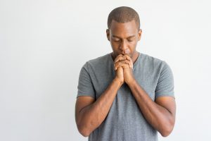 calm spiritual handsome african guy praying with closed eyes