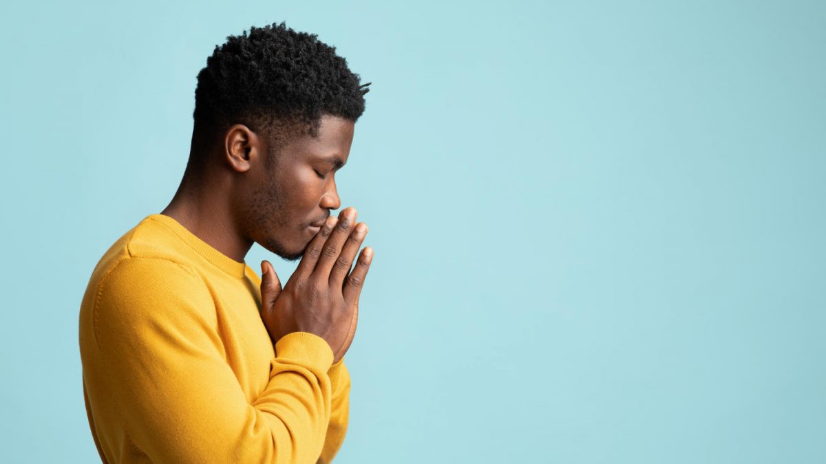 side view of praying african american young man copy space