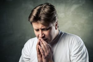 young man praying on dark studio background